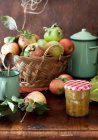 Vista close-up de tomate amarelo e maçã Chutney em uma mesa com uma cesta de maçãs frescas — Fotografia de Stock
