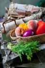 Verduras frescas y fruta en una cesta; racimo de eneldo fresco en una pila de madera - foto de stock