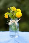 Jar of yellow Lantana flowers tied with twine outdoors — Stock Photo