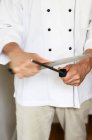 Vista de cerca de un chef afilando un cuchillo - foto de stock