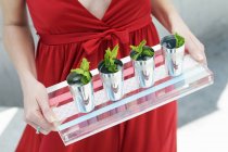 Cropped view of woman carrying a tray of iced mint drinks in cups — Stock Photo