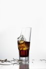 Closeup view of broken glass with Cola and ice cubes — Stock Photo