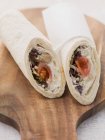 Wraps filled with houmous and tomatoes over wooden desk — Stock Photo