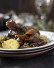 Closeup view of Coq au vin on stacked plates — Stock Photo