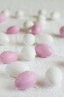 Vista close-up de ovos de açúcar branco e rosa espalhados — Fotografia de Stock