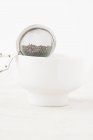 Colador de té equilibrado en el tazón - foto de stock