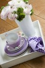 Vista elevada de flores em vaso por pilha de pratos e xícaras de café com doces — Fotografia de Stock