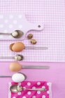 Top view of hen eggs and quail eggs on spoons — Stock Photo