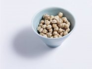 Grão-ervilhas em um prato branco sobre fundo branco — Fotografia de Stock