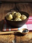 Vue rapprochée des boulettes de graines de pavot dans un bol et des graines de pavot dans une cuillère en bois — Photo de stock