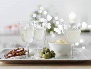 Spruzzatore di vino bianco in bicchieri di vino con stuzzichini — Foto stock
