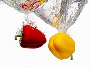 Peppers Splashing into Water — Stock Photo
