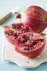 Red whole and a halved pomegranates — Stock Photo