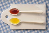 Top view of two spoons with oil and vinegar on a chopping board — Stock Photo
