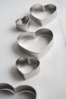 Vista close-up de cortadores de biscoito em forma de coração na superfície branca — Fotografia de Stock