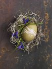 Vista superior de un huevo verde decorado para Pascua en un nido - foto de stock