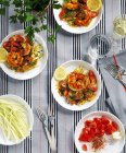 Crevettes avec salade de tomates sur assiettes blanches sur nappe — Photo de stock