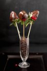 Closeup view of chocolate covered and skewered strawberries in glass of chocolate chips — Stock Photo
