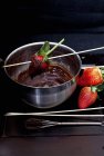 Vista de primer plano de chocolate derretido con fresas y fresas cubiertas de chocolate en el tazón - foto de stock