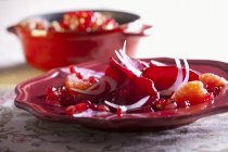 Beetroot carpaccio with pomegranate and grapefruit on red plate — Stock Photo