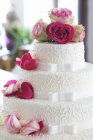 Gâteau de mariage décoré de roses fraîches — Photo de stock