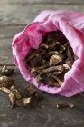 Vista close-up de cogumelos secos em um saco de pano rosa — Fotografia de Stock