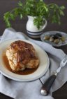 Жареная колбаса фаршированная куриная грудка; петрушка и оливки на белой тарелке поверх полотенца с вилкой — стоковое фото