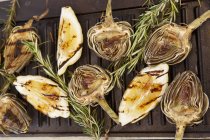 Grilled artichokes over black baking dish — Stock Photo