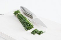 Bunch of fresh chives and knife — Stock Photo