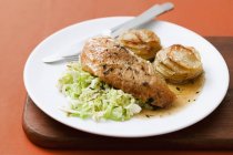 Petto di pollo con gratin di patate su piatto bianco sopra scrivania — Foto stock