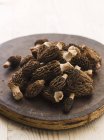 Closeup view of fresh morels on a round wooden board — Stock Photo