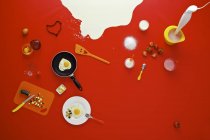 Verschiedene Frühstückszutaten über roter Oberfläche — Stockfoto