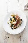 Guinea fowl wrapped in bacon with spinach on white plate with fork — Stock Photo