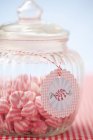 Vue rapprochée des bonbons à rayures roses et blanches dans un bocal en verre avec étiquette — Photo de stock