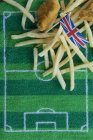 Pescado y patatas fritas (Inglaterra) con una bandera de papel Union Jack y decoración con temática de fútbol - foto de stock
