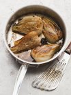 Pot-roast fennel in a saucepan over grey marble surface — Stock Photo