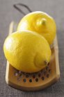 Свежие лимоны на деревянной терке — стоковое фото