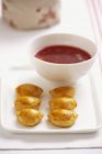 Yeast dumplings with a lentil and tomato filling and borscht in bowl over plate — Stock Photo