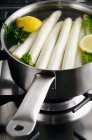 Peeled white asparagus in a saucepan with lemon and parsley — Stock Photo