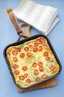 Potato tortilla with cherry tomatoes in baking tray over wooden desk — Stock Photo
