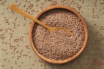 Top view of lentils in a bowl with a wooden spoon — Stock Photo