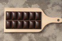 Barra de chocolate negro en la tabla de cortar - foto de stock