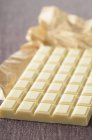 Bar of white chocolate with paper — Stock Photo