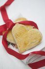 Closeup view of sweet heart-shaped cookies with red ribbon on towel — Stock Photo