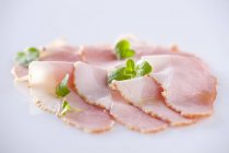 Slices of ham with oregano leaves — Stock Photo