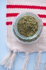 Top view of dried savory in glass jar on cloth — Stock Photo