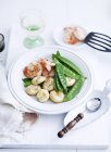 Saffron dumplings with shrimp and sugar snap peas on white plate over wooden desk — Stock Photo