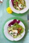Яєчний салат з огірком, помідорами, цибулею та радиккіо на білих тарілках над зеленою поверхнею — стокове фото