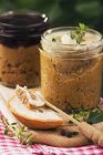 Closeup view of venison pate in jars with herb, bread and knife — Stock Photo