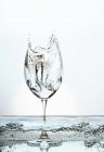 Vue rapprochée des éclaboussures dans un verre à vin rempli d'eau pétillante — Photo de stock
